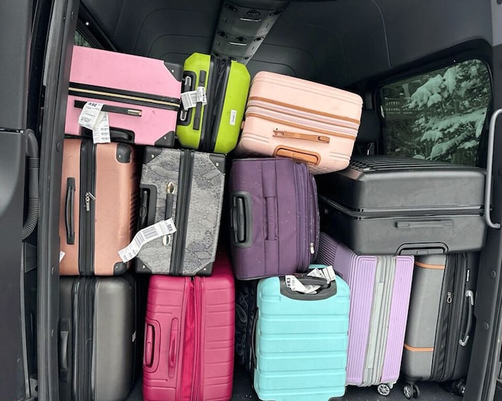 A variety of suitcases packed in a vehicle's cargo area. 5