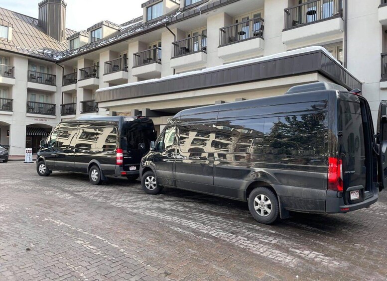 A black van parked in front of a multi-story building with balconies. 3