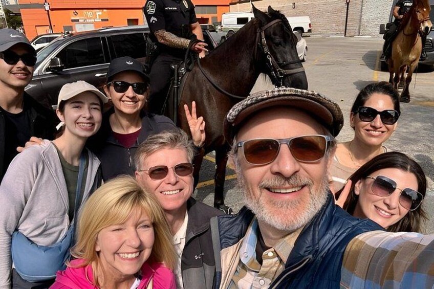 A group of people posing with a horse in an urban setting. 1