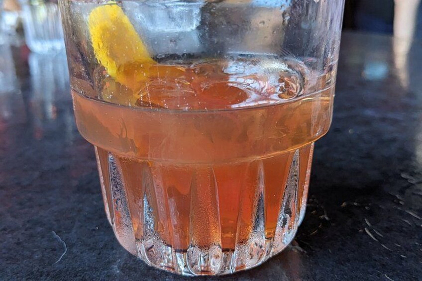 A glass of amber-colored beverage with ice cubes and a lemon slice. 3