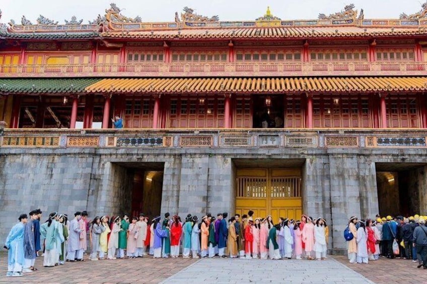 Un grupo de personas vestidas con atuendos tradicionales posando frente a un templo con una gran puerta dorada. 1