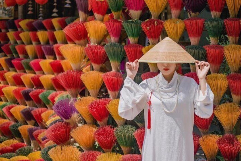 Una persona vestida con traje tradicional sostiene un sombrero cónico, rodeada de varios abanicos coloridos. 2