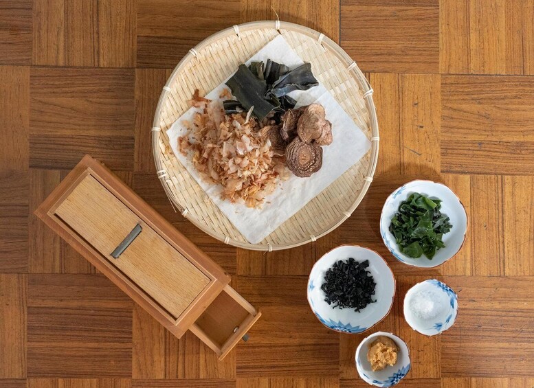 A traditional Japanese meal with a bamboo basket, sliced fish, seaweed, and small bowls of wasabi, pickled ginger, and soy sauce. 4