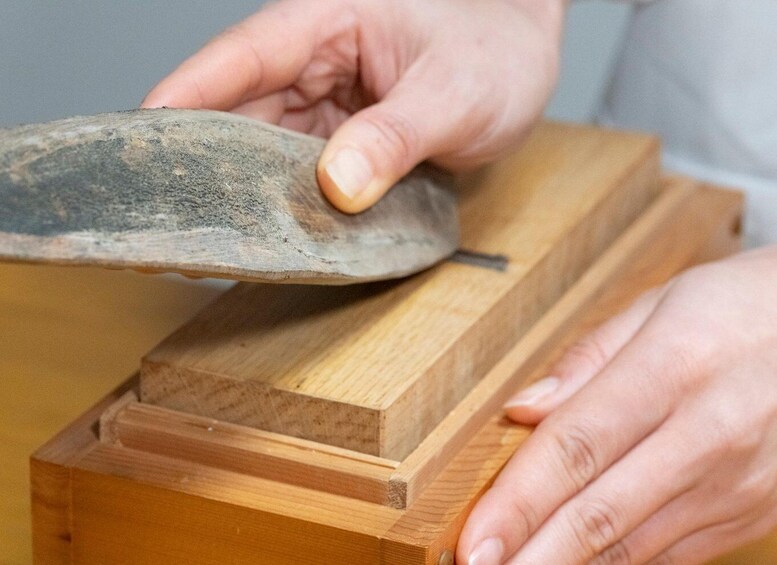 A person sharpening a knife on a wooden block. 5
