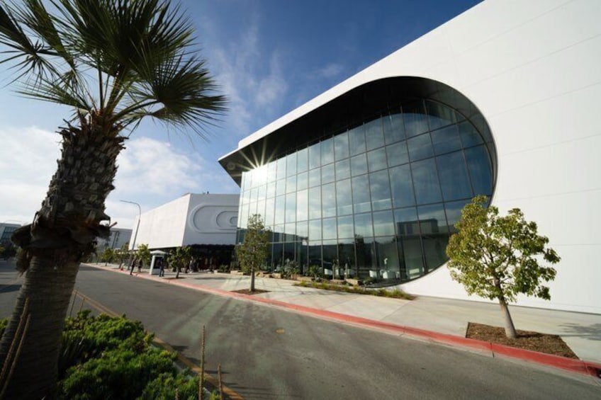 A modern building with a curved glass facade, palm trees, and a clear sky. 4