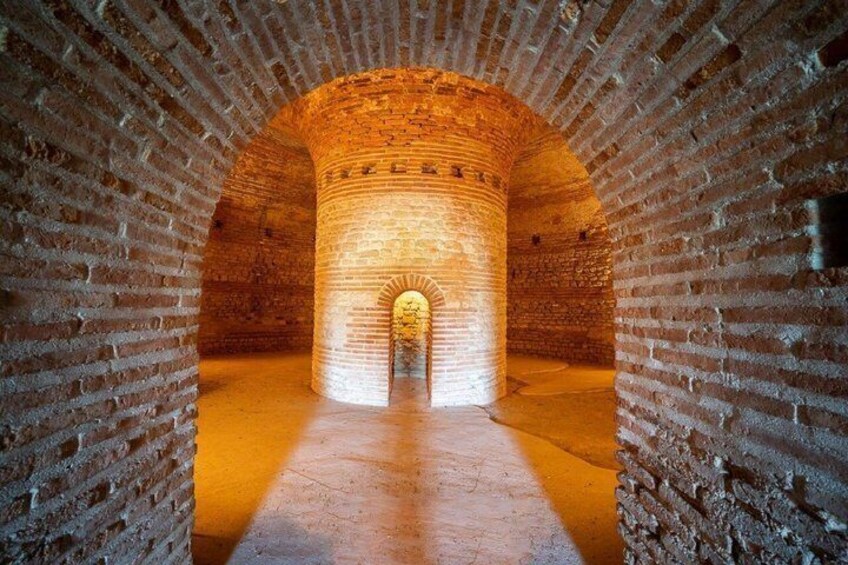 A brick tunnel with a circular archway at the end. 5