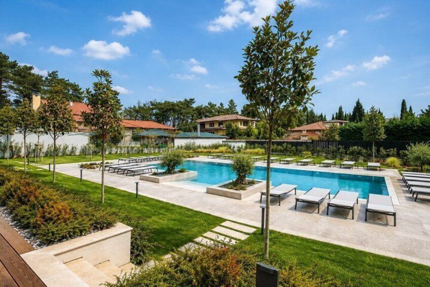 A swimming pool with lounge chairs, surrounded by a landscaped garden and residential buildings. 4