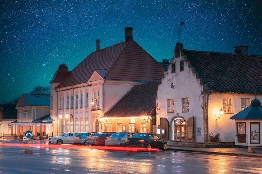 Un edificio histórico con techo rojo y paredes blancas, iluminado por luces cálidas bajo un cielo nocturno estrellado. 3