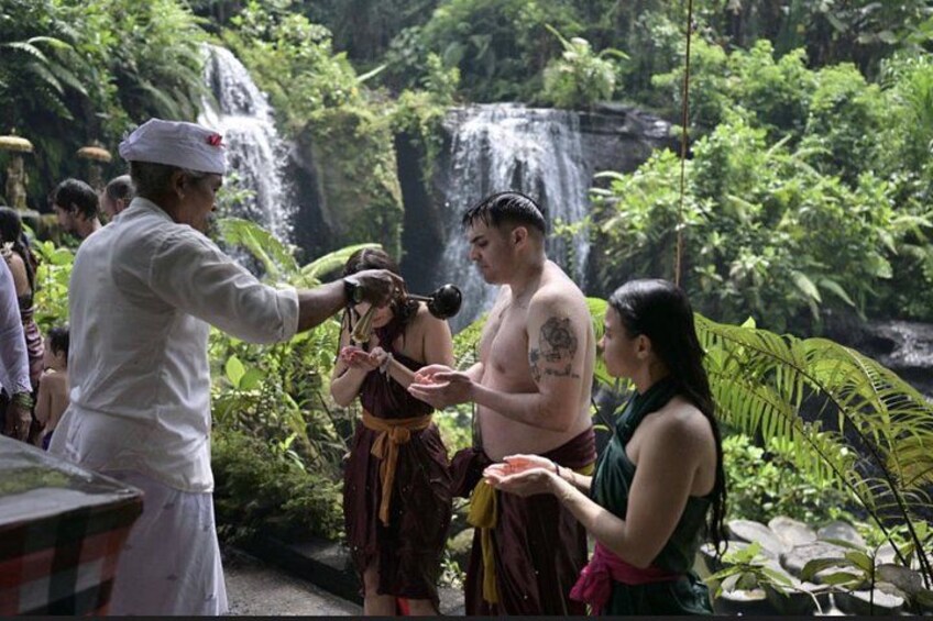A waterfall, lush greenery, and people in traditional attire. 5
