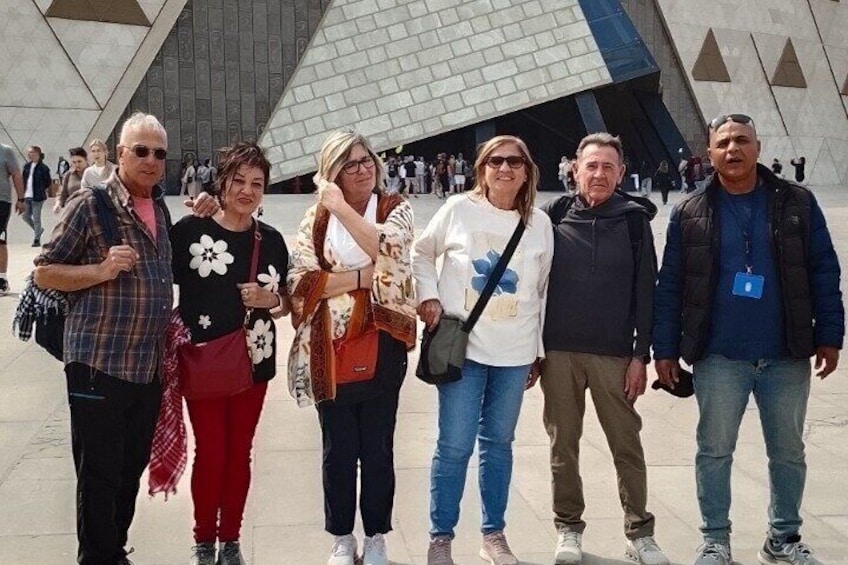 A group of people standing in front of a modern architectural structure with a geometric design. 3