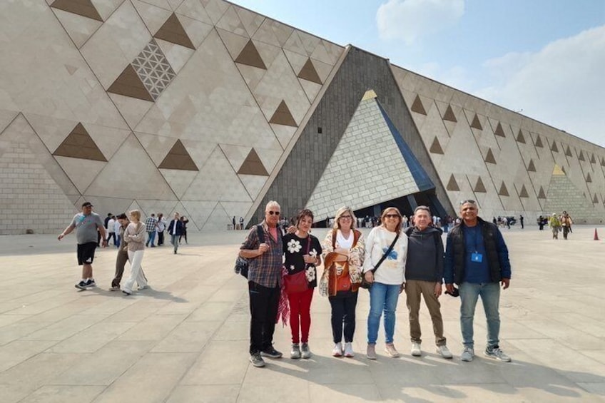 A group of people standing in front of a large, modern building with a distinctive triangular design. 2