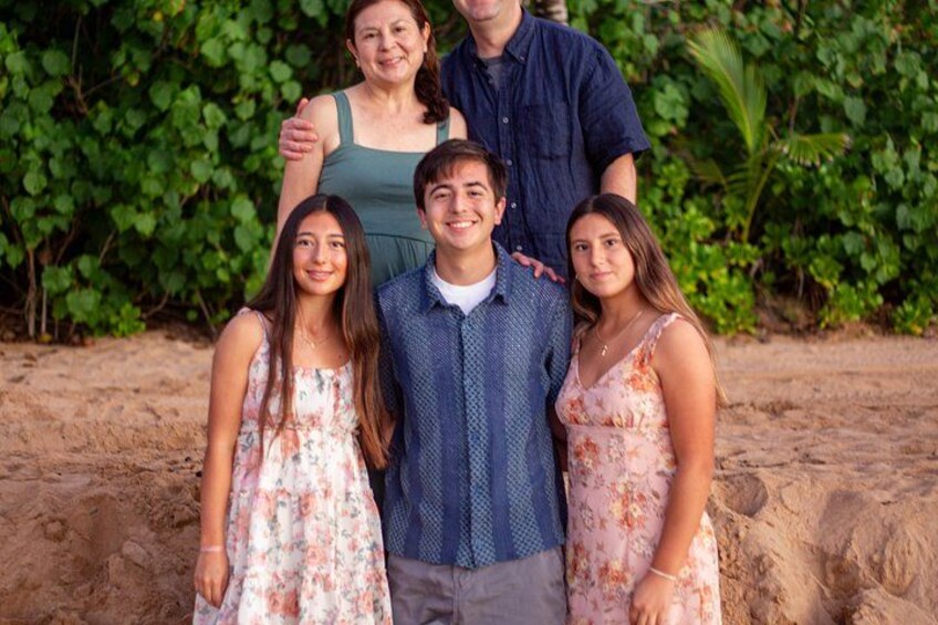 Una famiglia di quattro persone su una spiaggia sabbiosa, con fitta vegetazione sullo sfondo. 4