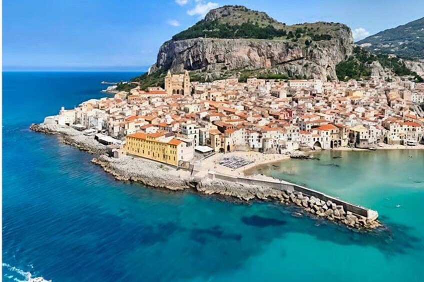 Un pueblo costero con una iglesia destacada, un acantilado rocoso y un mar azul cristalino. 1