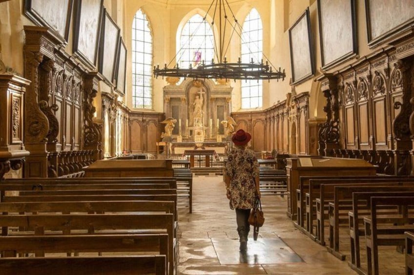 An interior of a church with wooden pews, a central aisle, and a large altar at the far end. 5