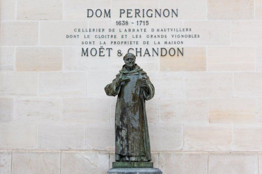 A statue of Dom Perignon with a plaque. 1