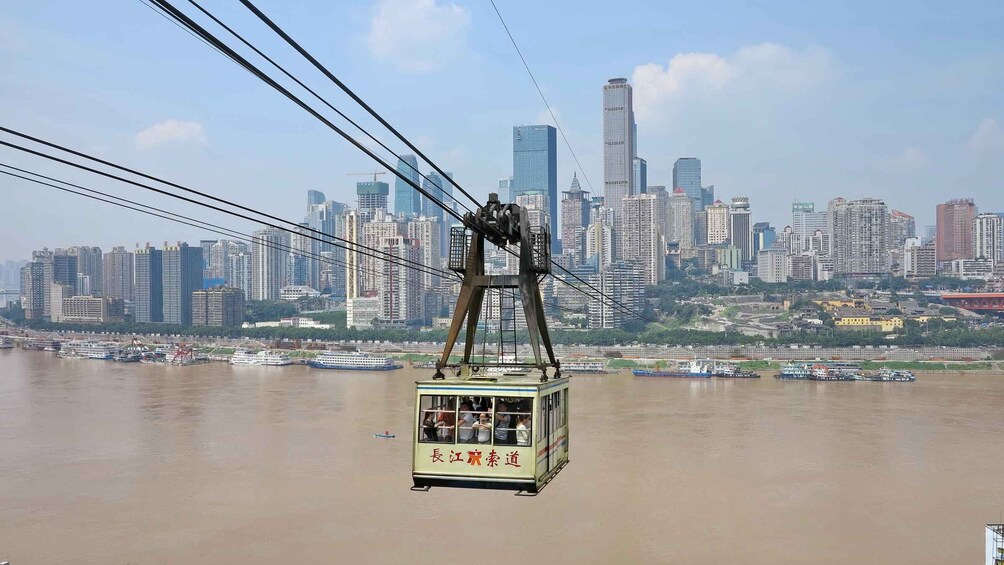 A cable car moving over a river with a city skyline in the background. 5