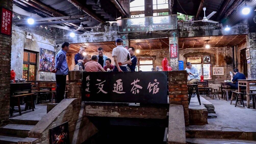 A bustling indoor market with wooden stalls and a sign indicating a tea shop. 4