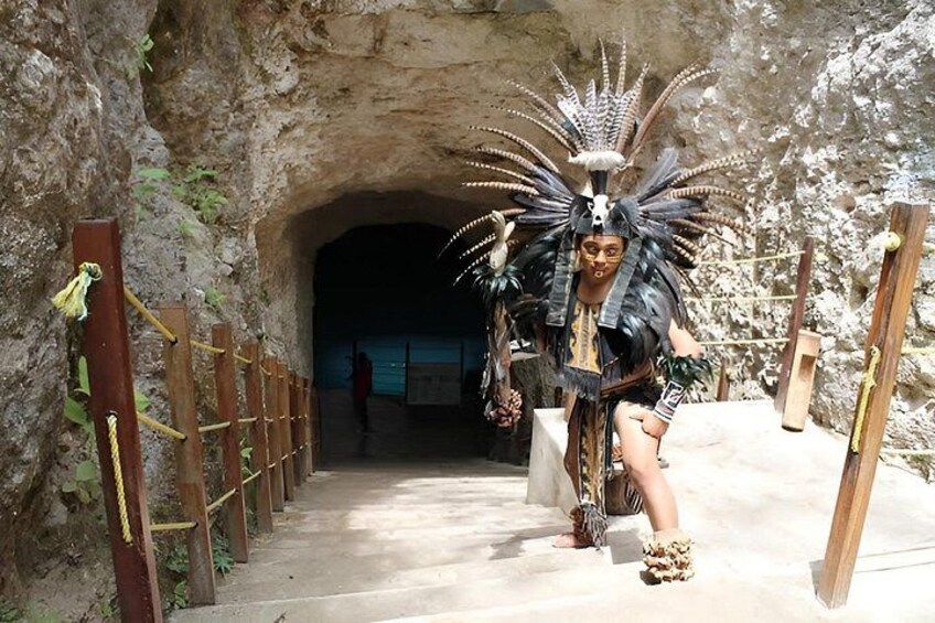 A person in elaborate traditional attire walking through a tunnel with a wooden fence on the left. 4