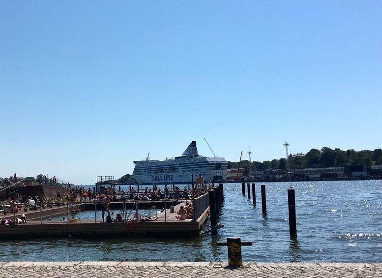 A cruise ship docked at a pier with people on the pier and a clear blue sky. 5