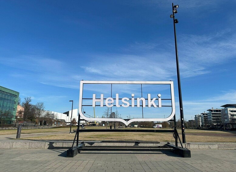 A large sign with 'Helsinki' written on it, set against a clear blue sky. 1