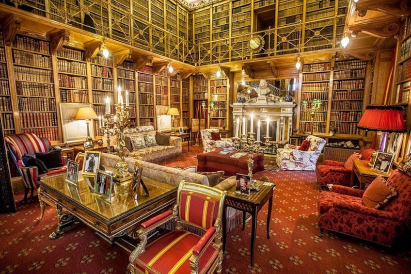 A library with bookshelves, a fireplace, and a red carpeted floor. 3