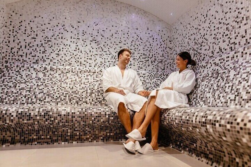 Two people sitting on a mosaic-tiled bench in a spa. 4