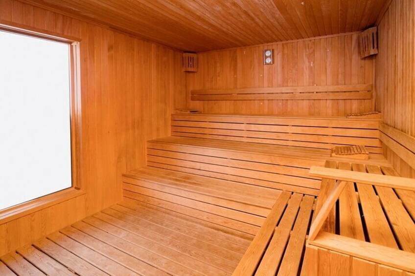A wooden sauna with benches and a large window. 5
