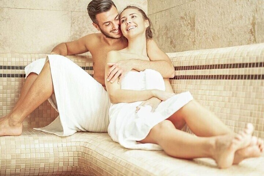 A couple sitting on a tiled bench in a public bath area. 2
