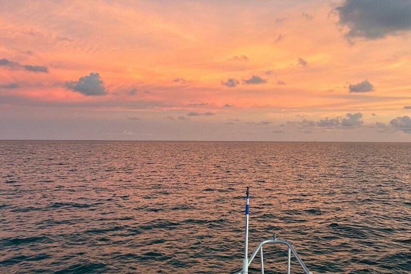 Un coucher de soleil sur l’océan, avec un bateau au premier plan. 2