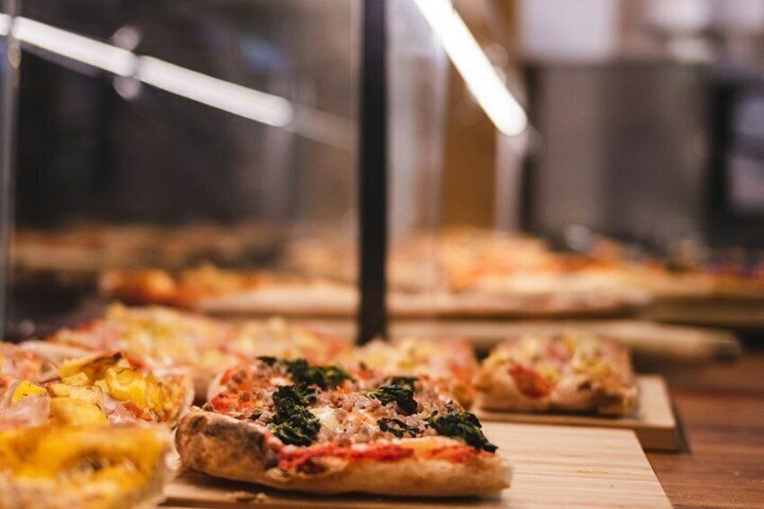 Verschillende pizza's staan uitgestald in een glazen vitrine. 5