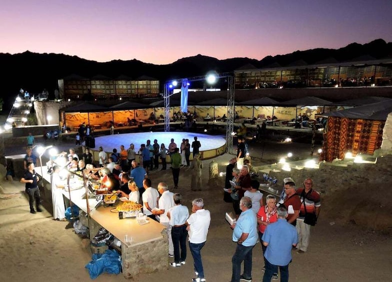 A nighttime outdoor event with a stage and audience. 3