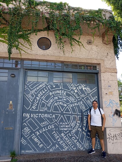 A man standing in front of a graffiti-covered wall with a map of European cities. 3