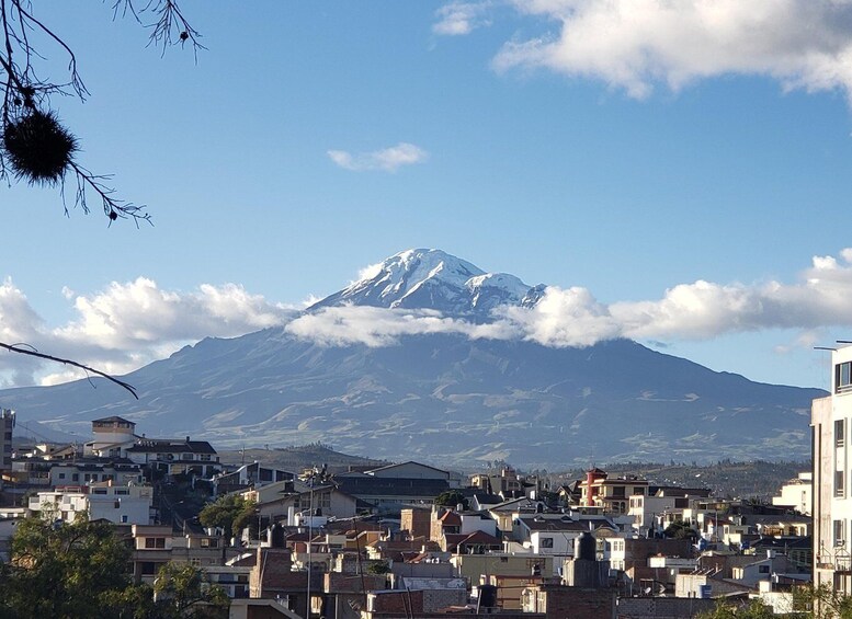 A snow-capped mountain, a town with buildings, and a clear sky. 1