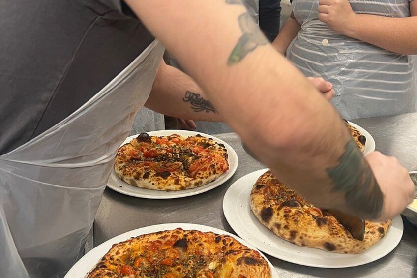 Iemand snijdt een pizza op een tafel. 4