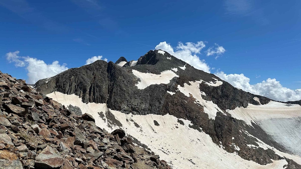 A rugged mountain with snow patches and rocky terrain under a clear blue sky. 3