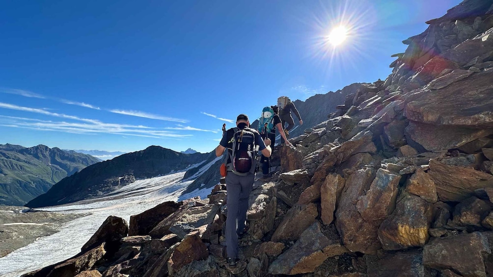Hikers on a rocky mountain trail with a glacier in the valley. 2