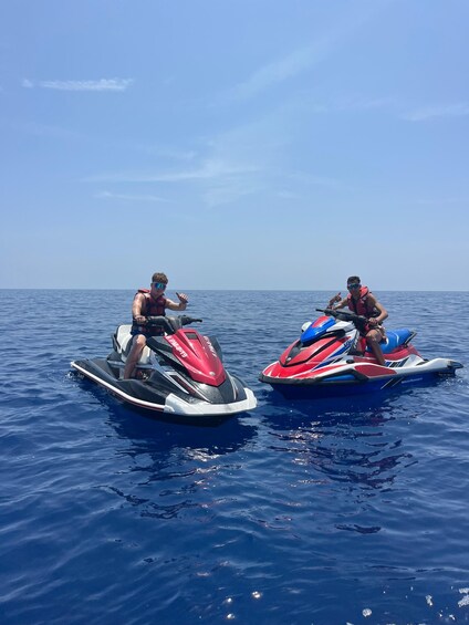 Two people jet skiing on a calm sea under a clear sky. 1