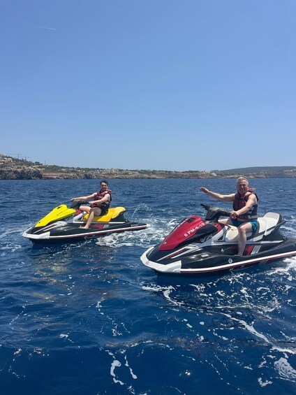 Two people jet-skiing on a clear day with a coastal landscape in the background. 5