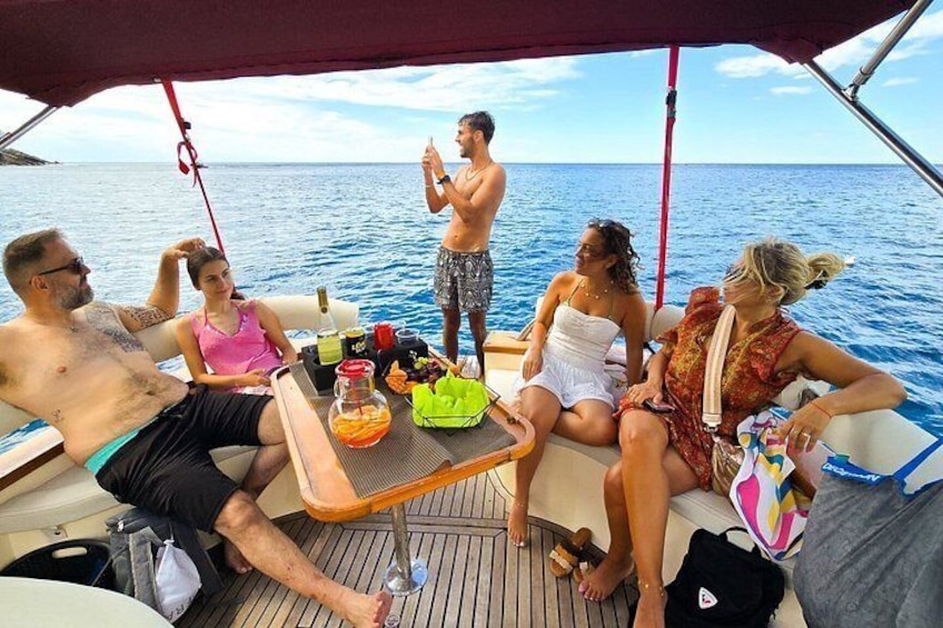 A group of people on a boat with a table set with drinks and snacks. 3