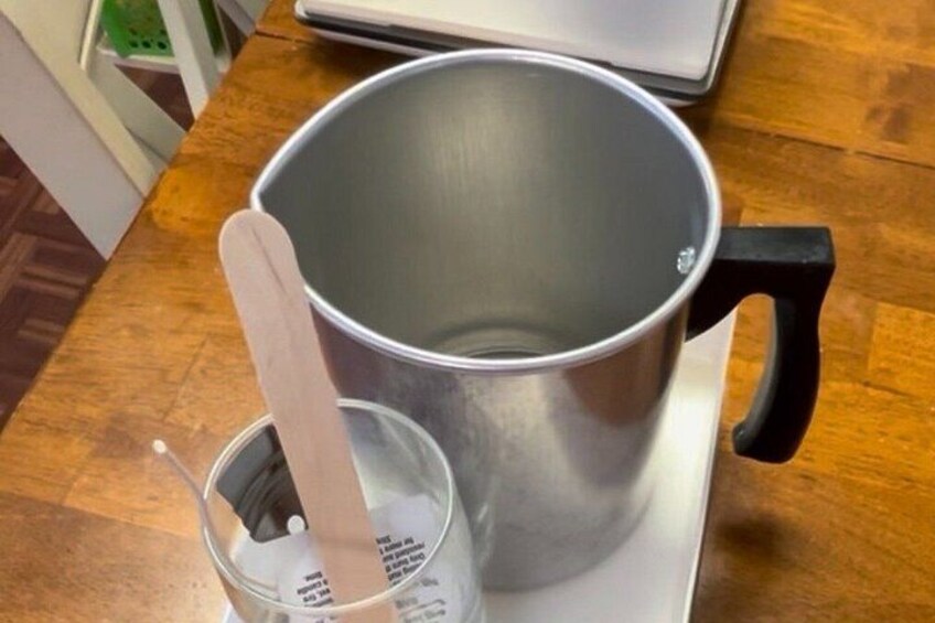 Una olla de acero inoxidable con mango de madera sobre una superficie blanca. 3