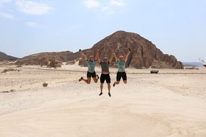 Two people jumping in a desert with rocky mountains in the background. 5
