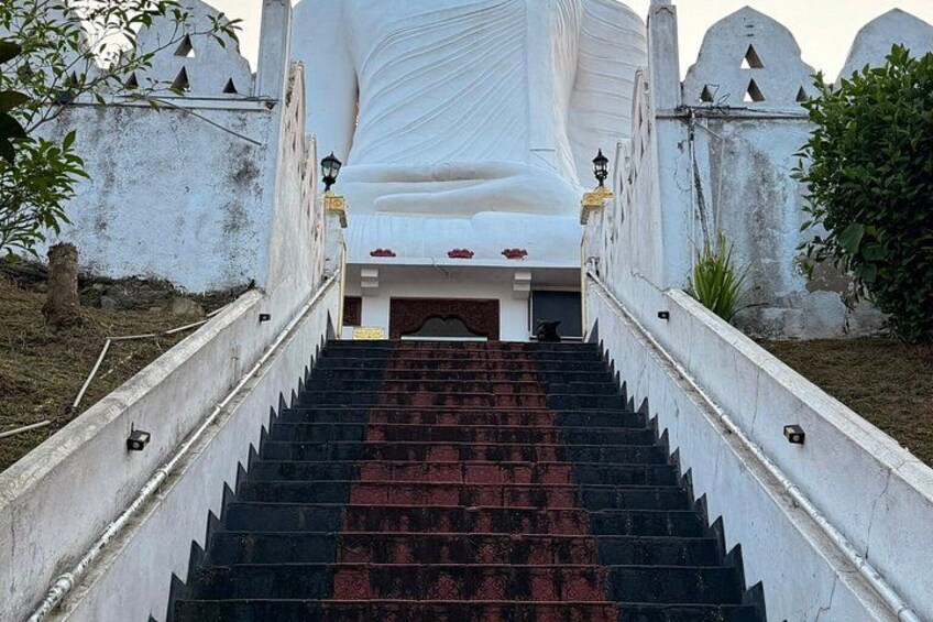 A large white statue with a red carpet leading up to it, surrounded by white walls and a staircase. 4