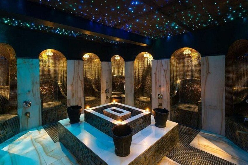 A spa with a central square, four arched seating areas, and a ceiling adorned with lights. 5