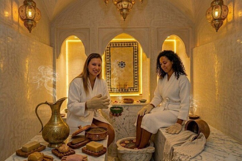 Two people in a spa setting with traditional decor, including a patterned wall, a brass pitcher, and a bowl. 3