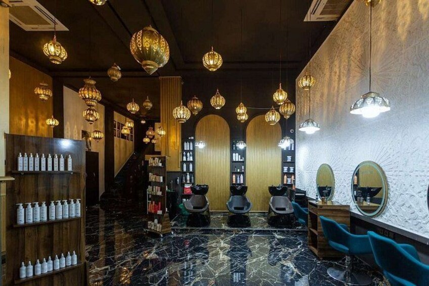A salon interior with marble floors, hairdressing chairs, and pendant lighting. 2