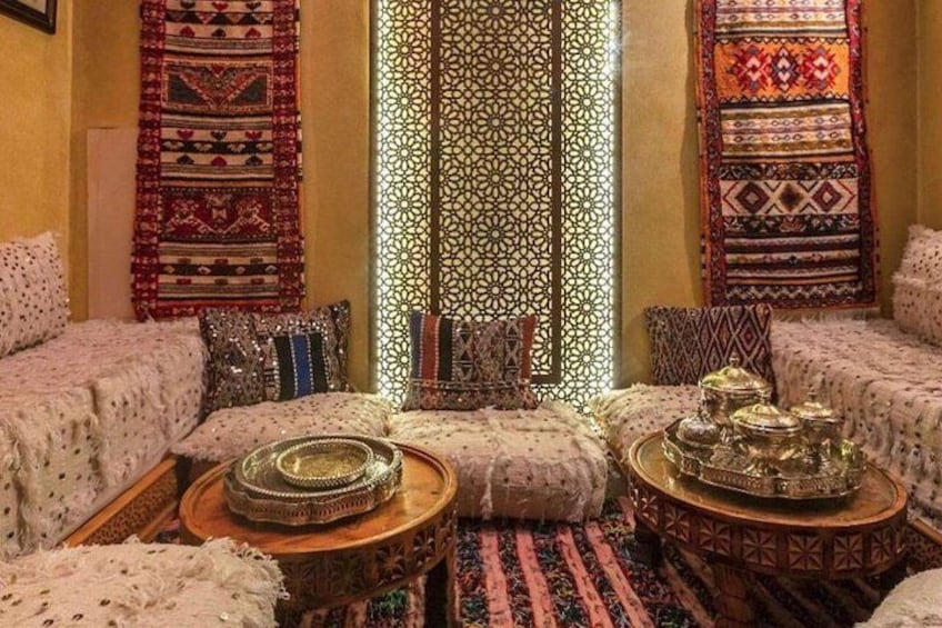 A traditional interior with patterned textiles, cushions, and ornate metal containers. 5