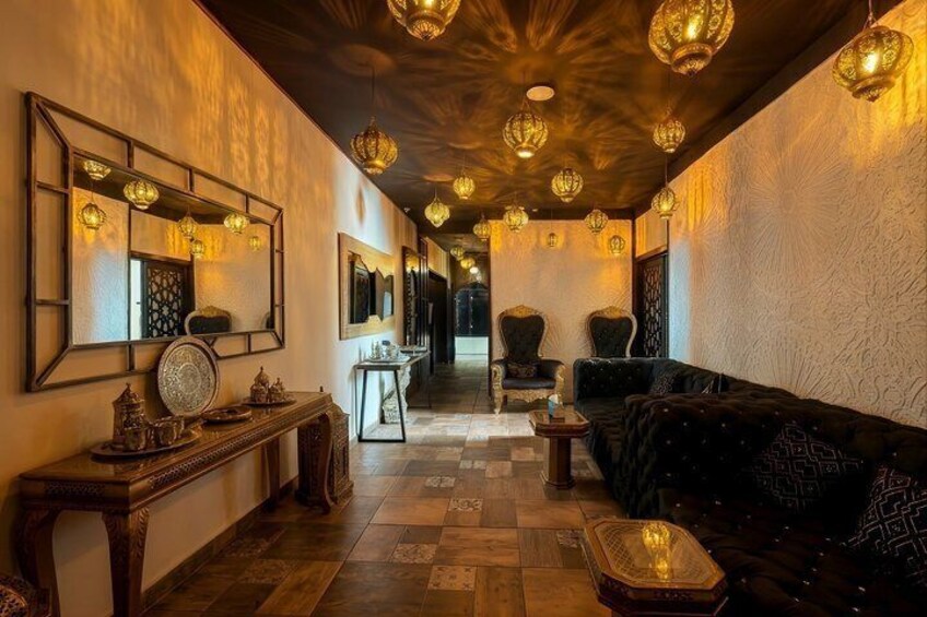 A warmly lit interior with a wooden floor, a black sofa, and traditional decor. 4