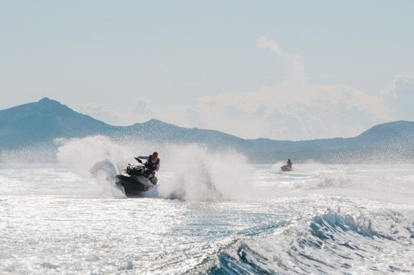 Una persona conduciendo un jet ski sobre un lago nevado con montañas al fondo. 2
