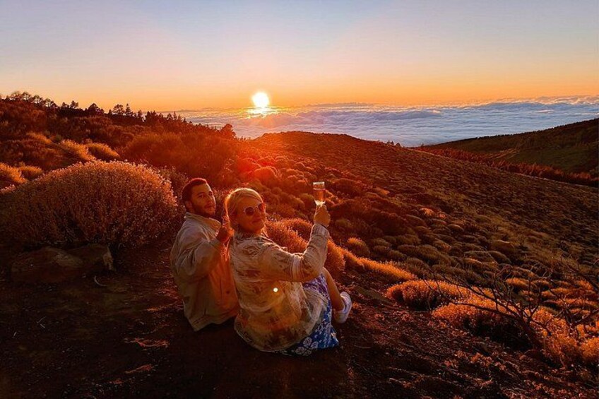 Dos personas sentadas en una colina cubierta de hierba durante la puesta de sol. 1