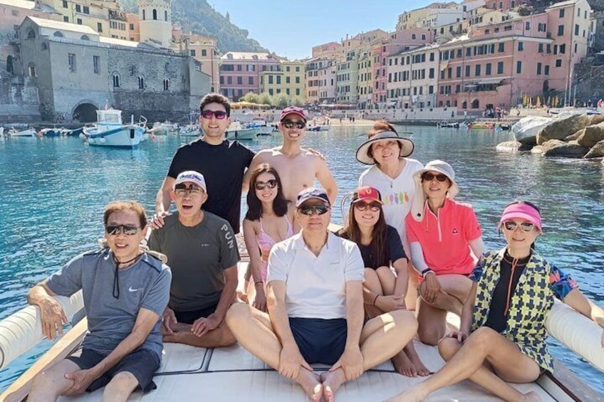 Un grupo de personas en un bote en un pueblo costero con edificios históricos y embarcaciones al fondo. 1